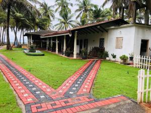 a house with a brick walkway in front of a yard at New Romantic Beach Hotel in Toduwawa South