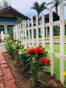 a white fence with flowers in front of a house at New Romantic Beach Hotel in Toduwawa South