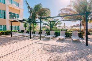 a patio with white chairs and a pergola at Aruba Life 315 in Noord