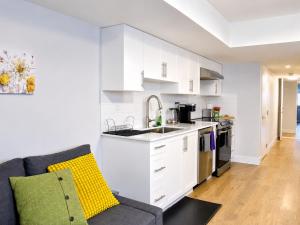 a kitchen with white cabinets and a couch at Centrally Located Modern Suite in North Vancouver