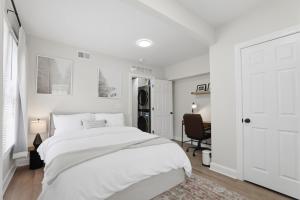 a white bedroom with a large bed and a desk at Keifer Suite in Detroit