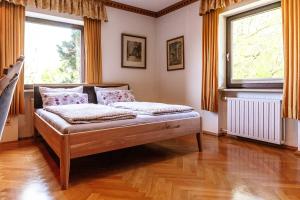 a bed in a room with two windows at Landhausvilla Watzmannblick in Saaldorf-Surheim