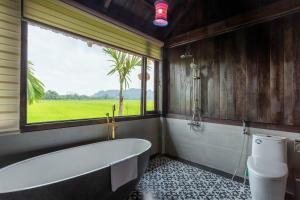 a bathroom with a bath tub and a window at The Palm Tree Bungalow in Xuân Sơn