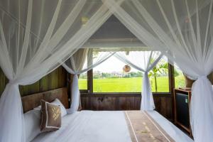 a bedroom with a canopy bed with a window at The Palm Tree Bungalow in Xuân Sơn