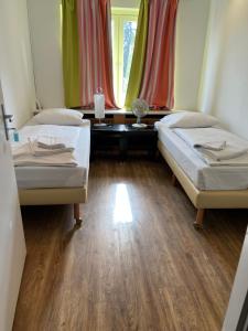 a room with two beds and a table and a window at Pension Passion Julie in Berlin