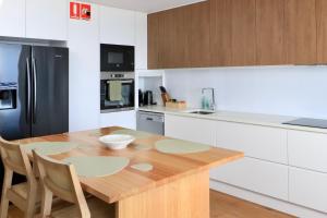 a kitchen with a wooden table and a black refrigerator at Tranquillity On The Promenade in Batemans Bay