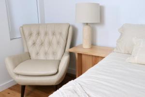 a bedroom with a chair next to a bed at Tranquillity On The Promenade in Batemans Bay