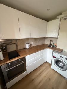a kitchen with white cabinets and a washing machine at Harmony Apartments Lux in Liepāja