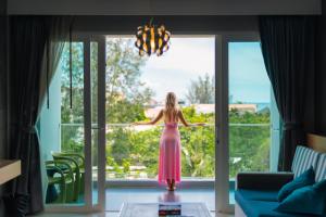 a woman in a pink dress standing in front of a window at Ratana Platinum Resort Kamala in Kamala Beach +109 photos