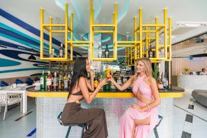 two women sitting at a bar with drinks at Ratana Platinum Resort Kamala in Kamala Beach