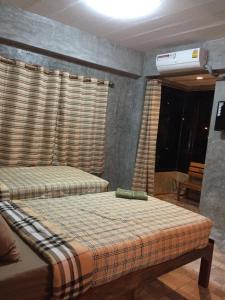 a bedroom with two beds in a room with windows at Chiangmai HomeTeL in Chiang Mai