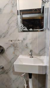 a bathroom with a white sink and a mirror at Hotel SR & restaurant in Bhauvāpār