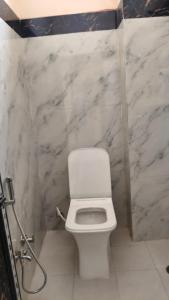 a bathroom with a white toilet and marble walls at Hotel SR & restaurant in Bhauvāpār