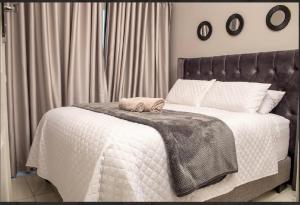 a bedroom with a white bed with a black headboard at MbaliBliss at Selborne in Bulawayo