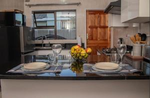 a kitchen with a table with plates and a bowl of fruit at MbaliBliss at Selborne in Bulawayo