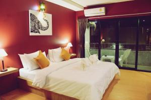 a bedroom with a large white bed with red walls at At Home Khaolak in Khao Lak