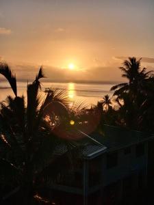 a sunset from the balcony of a resort with palm trees at Sunrise Home in Savusavu