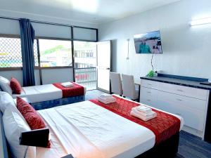 a hotel room with two beds and a television at Tropical Gateway Motor Inn in Rockhampton