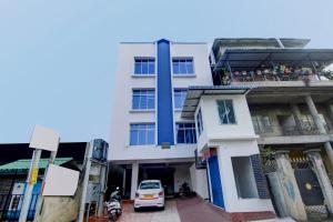 a white building with a car parked in front of it at Hotel O Sai villa in Dispur