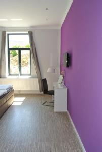 Zimmer mit lila Wänden, einem Bett und einem Schreibtisch in der Unterkunft Gästehaus Tappes Hofgarten in Sinzig