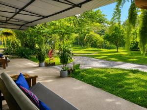 a patio with a couch and a lawn with trees at Los Susurros. Casa in Palenque
