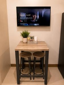 a table with two stools and a tv on a wall at Stylish 1BR Condo @ SM Southmall in Manila
