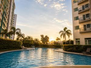 a swimming pool in a resort with palm trees and buildings at Stylish 1BR Condo @ SM Southmall in Manila