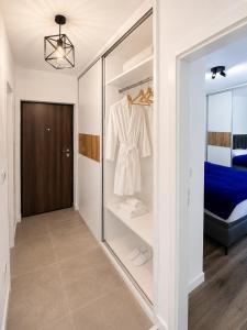 a walk in closet with a white shirt and a bed at Urban Nest Tuzla in Tuzla