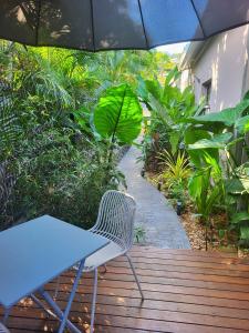 a blue table and a chair on a wooden deck with an umbrella at Le Studio Joli in La Possession