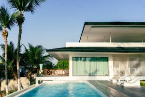 a villa with a swimming pool in front of a house at Hôtel Touraco in Assinie