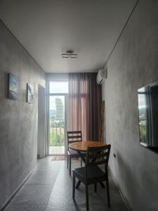 a dining room with a table and chairs and a window at Batumi View apartment in Kachretʼi