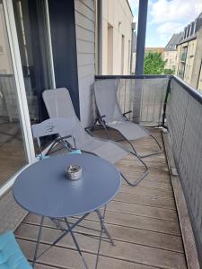 three chairs and a table on a balcony at Gite des Capucines in Bourbourg
