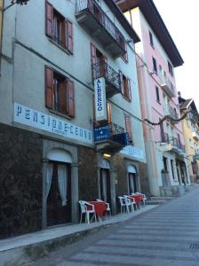 un bâtiment avec des tables et des chaises dans une rue dans l'établissement Albergo Cervo, à Ponte di Legno