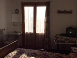 Schlafzimmer mit einem Bett, einem Fenster und einem Waschbecken in der Unterkunft Albergo Cervo in Ponte di Legno