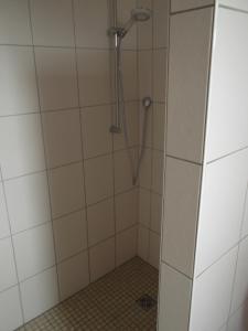 ein Bad mit einer Dusche und weißen Fliesen in der Unterkunft Gute Nacht Ferienwohnung in Halle Westfalen