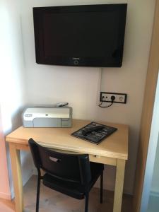 a desk with a television on a wall with a chair at Messe Ferienwohnung Düsseldorf Oberkassel in Düsseldorf