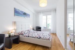 a white bedroom with a bed and a chair at Nice Beach - Promenade Des Anglais in Nice