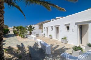 a white building with palm trees in front of it at Lithos Suites Sifnos in Kamares