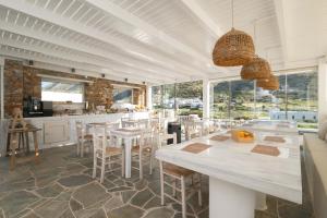 a dining room with tables and chairs and windows at Lithos Suites Sifnos in Kamares