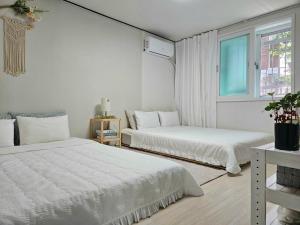 two beds in a white room with a window at 행궁동-House2 in Suwon