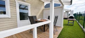 a patio with a table and chairs and a grill at Domki 7 Houses Rewal in Rewal