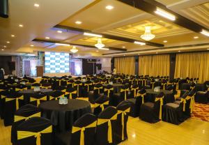a large banquet hall with black tables and chairs at Hotel Devanshi & Banquets by Classy Stay in Navi Mumbai