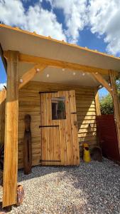 a wooden shed with a large wooden door at Roulotte Providence in Boudeville