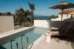a swimming pool with a chair and an umbrella at Aktis Seaside Living in Iraklitsa
