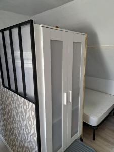 a small white cabinet with a bench in a room at Studio d hotes 2 ème étage in Carantec