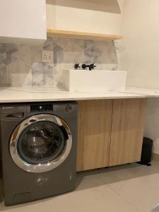a washing machine in a kitchen with a sink at RiverfrontOasis - Huge Backyard, Pool, Grand Piano in Sandton