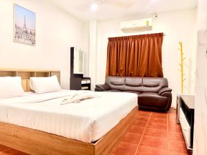 a bedroom with a bed and a leather chair at Vista Inn Patong in Patong Beach
