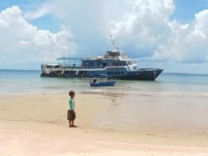 a little boy standing on the beach with a large ship at Anna Koh Rong in Kaôh Rŭng (3)