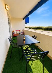 a balcony with a table and chairs and a couch at Charmant appartement en front de mer avec piscine in Lacanau-Océan