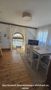 a dining room with a table and chairs and a window at Syrenka Apartamenty in Ustka